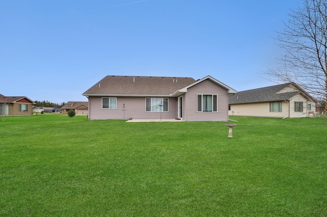 back of house with a lawn, a shingled roof, and a patio area