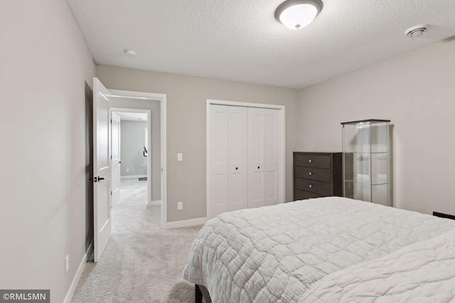 bedroom featuring light colored carpet, a closet, and a textured ceiling