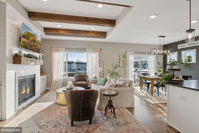 living room with light hardwood / wood-style flooring, a chandelier, and beamed ceiling