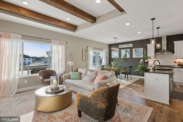 living room featuring sink, dark hardwood / wood-style floors, a wealth of natural light, and beam ceiling