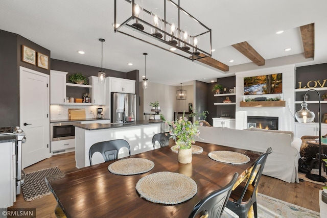 dining area with beamed ceiling, a large fireplace, and dark hardwood / wood-style flooring