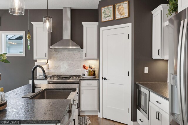 kitchen with pendant lighting, wall chimney exhaust hood, stainless steel fridge, and white cabinets