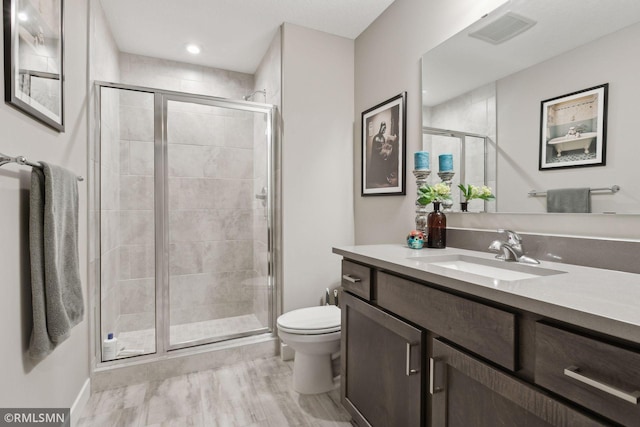 bathroom featuring vanity, a shower with door, and toilet