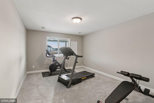 exercise area featuring light colored carpet and a textured ceiling