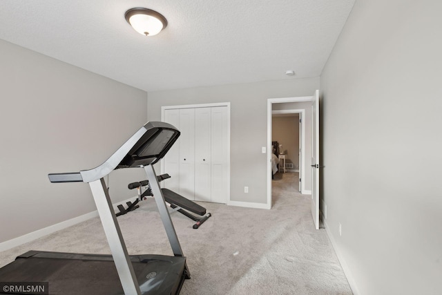 exercise room featuring light colored carpet and a textured ceiling