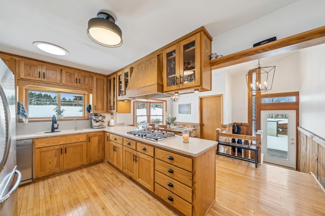 kitchen with an inviting chandelier, decorative light fixtures, light wood-type flooring, appliances with stainless steel finishes, and kitchen peninsula