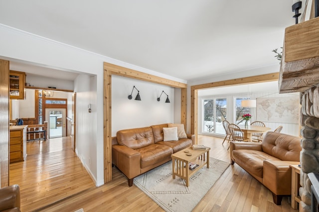 living room featuring crown molding, baseboards, and light wood-style floors