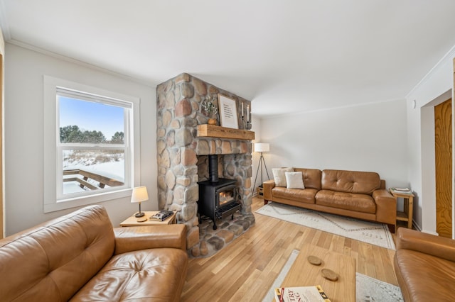 living room with wood-type flooring, ornamental molding, and a wood stove