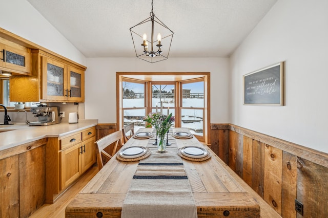 dining room with an inviting chandelier, sink, light hardwood / wood-style floors, and vaulted ceiling