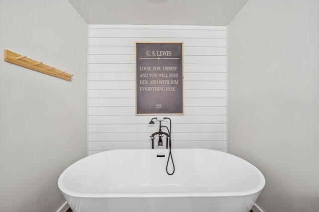 bathroom featuring a bathtub and wooden walls