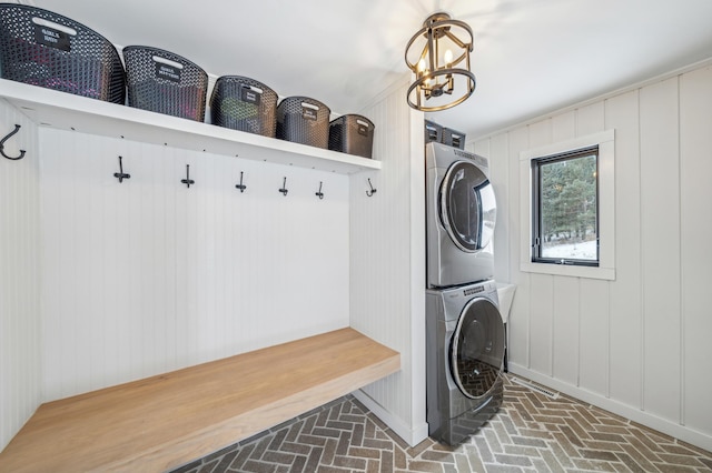 mudroom featuring stacked washing maching and dryer and a chandelier