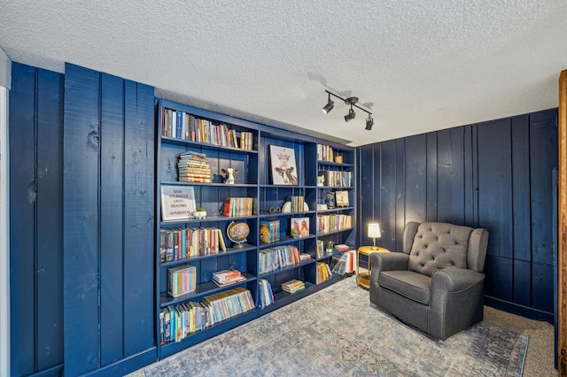 living area featuring built in features, wood walls, a textured ceiling, and carpet flooring