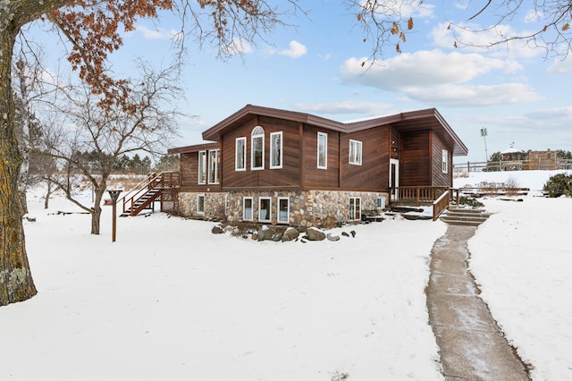 view of snow covered exterior with stone siding