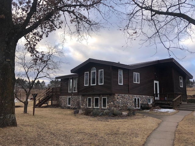 view of side of property featuring stairs and stone siding