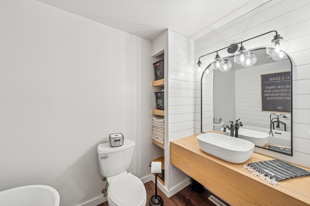 bathroom with toilet, baseboards, wood finished floors, and vanity