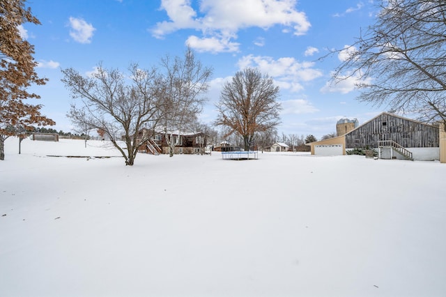 yard covered in snow with stairs, a trampoline, and a garage