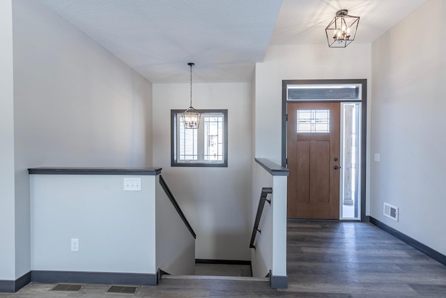 foyer entrance with an inviting chandelier, dark hardwood / wood-style floors, and a healthy amount of sunlight