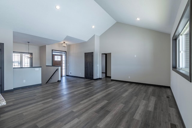 unfurnished living room featuring dark hardwood / wood-style flooring, high vaulted ceiling, and a notable chandelier