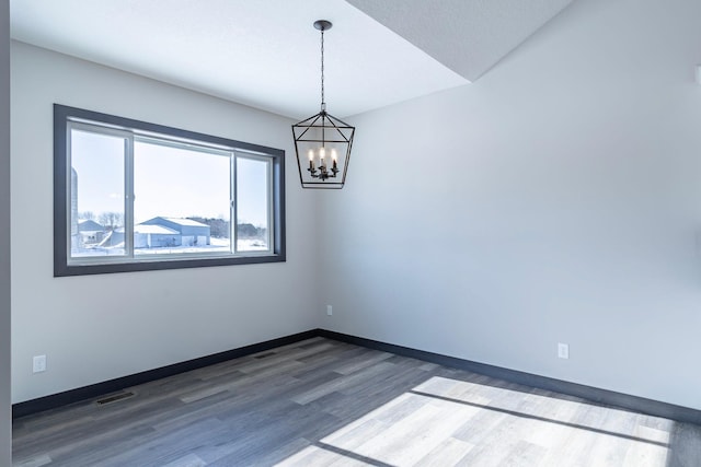 unfurnished room with a chandelier and dark hardwood / wood-style flooring