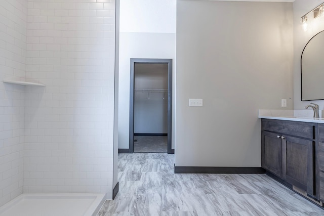 bathroom with vanity, hardwood / wood-style flooring, and a tile shower