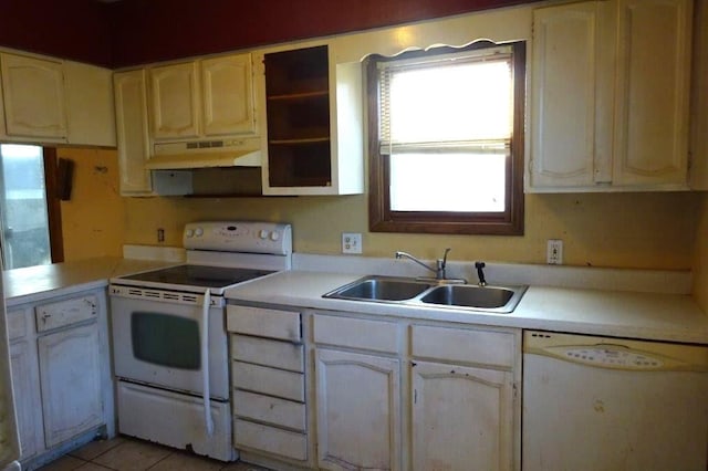 kitchen with sink, white appliances, light tile patterned floors, and kitchen peninsula