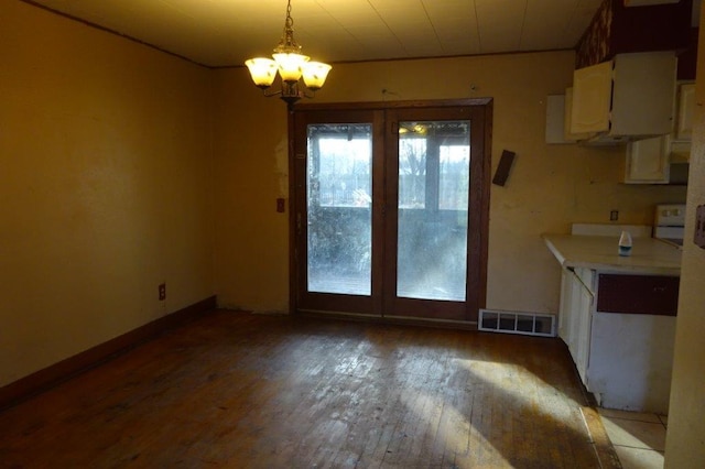 unfurnished dining area featuring wood-type flooring and a notable chandelier