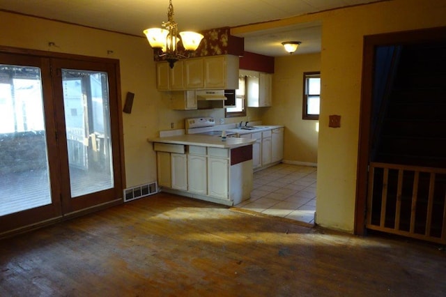 kitchen featuring sink, light hardwood / wood-style flooring, electric range, white cabinets, and decorative light fixtures