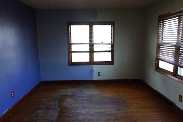 spare room with dark wood-type flooring and a wealth of natural light