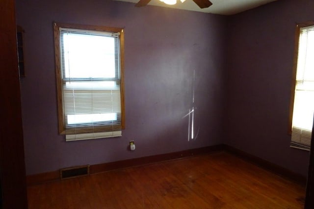 empty room with ceiling fan, plenty of natural light, and wood-type flooring