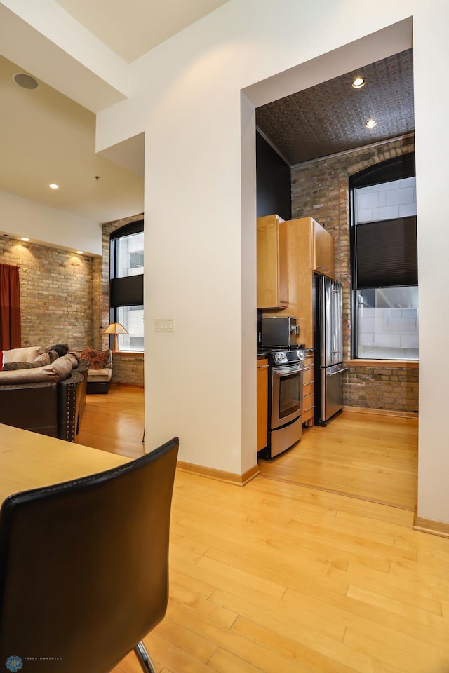 12 Broadway N Unit 206, Fargo, ND 58102 - kitchen with appliances with stainless steel finishes, brick wall, light wood-style floors, open floor plan, and baseboards