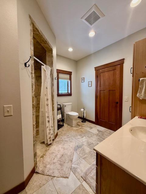 E2614 Bohland Hollow Rd, Wheatland Twp, WI 54624 - full bath featuring toilet, curtained shower, vanity, baseboards, and recessed lighting