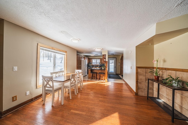 dining area with a textured ceiling, baseboards, and wood finished floors