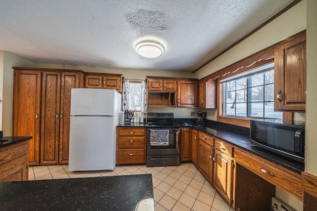 kitchen featuring light tile patterned floors, freestanding refrigerator, range with electric cooktop, black microwave, and plenty of natural light