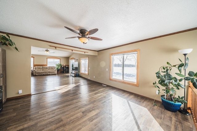 unfurnished living room featuring a textured ceiling, ornamental molding, wood finished floors, and baseboards