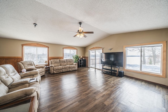 unfurnished living room featuring dark wood finished floors, wainscoting, vaulted ceiling, a textured ceiling, and ceiling fan