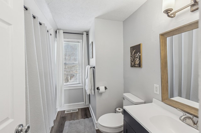 bathroom featuring vanity, toilet, wood-type flooring, and a textured ceiling