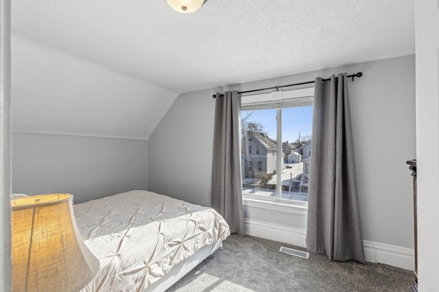 bedroom featuring vaulted ceiling, carpet, and a textured ceiling