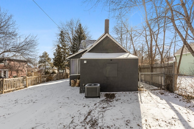 snow covered back of property featuring central AC unit