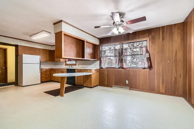 kitchen with brown cabinets, ceiling fan, light countertops, wood walls, and freestanding refrigerator