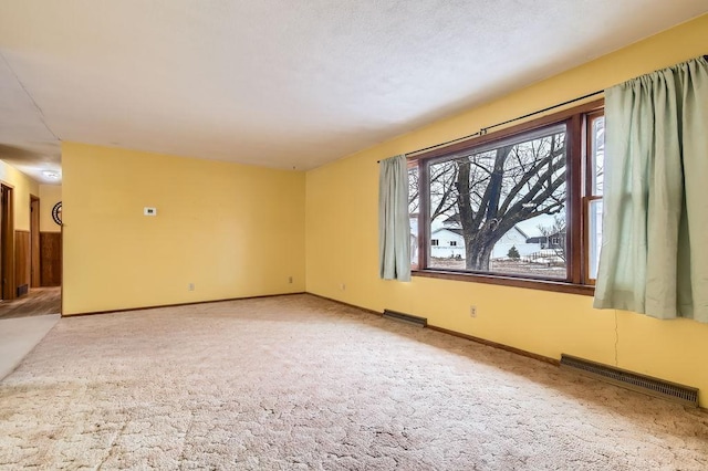 unfurnished room with carpet floors, visible vents, and baseboards