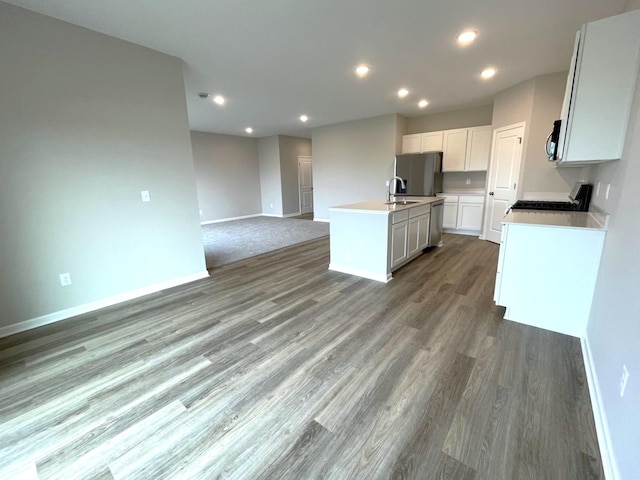 kitchen featuring sink, appliances with stainless steel finishes, white cabinets, a center island with sink, and dark hardwood / wood-style flooring