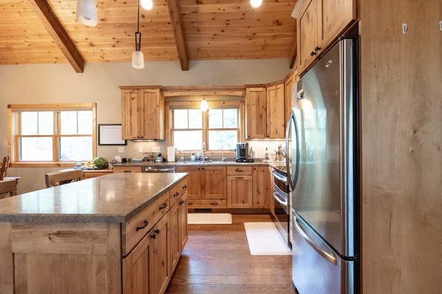 kitchen featuring appliances with stainless steel finishes, vaulted ceiling with beams, a kitchen island, decorative light fixtures, and wooden ceiling