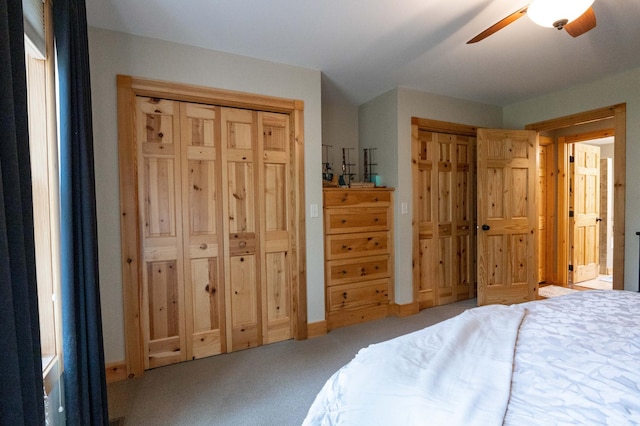 carpeted bedroom featuring multiple closets and ceiling fan