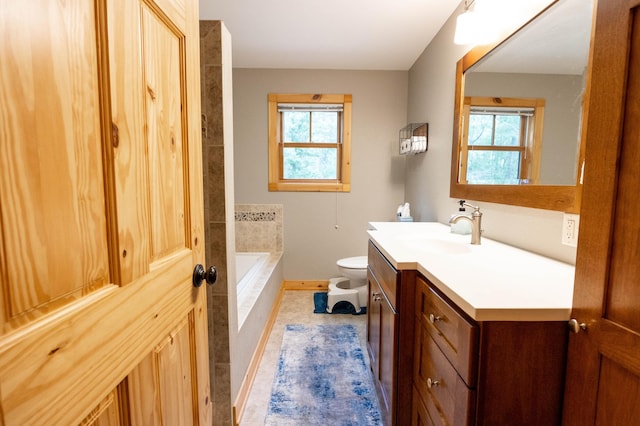 bathroom with vanity, plenty of natural light, tiled bath, and toilet