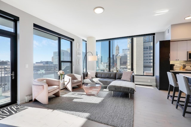 living room with a city view, visible vents, light wood-style floors, and a baseboard radiator