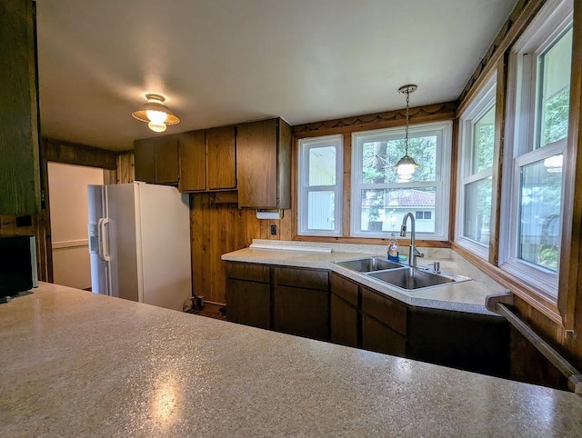 kitchen featuring white refrigerator with ice dispenser, sink, and decorative light fixtures