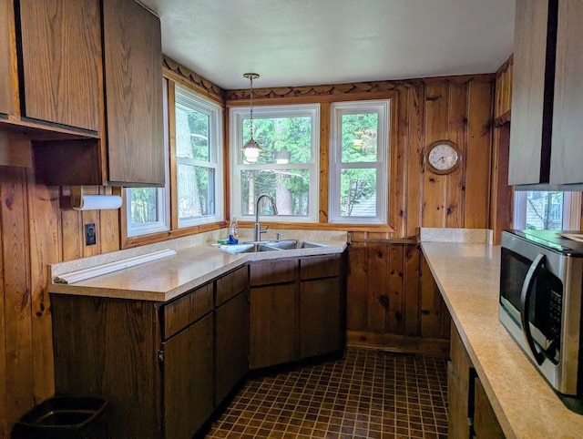 kitchen with wooden walls, decorative light fixtures, and sink