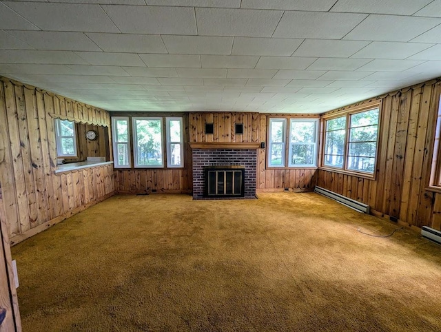 unfurnished living room with a healthy amount of sunlight, a baseboard heating unit, a brick fireplace, and carpet