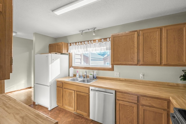 kitchen with sink, a textured ceiling, white refrigerator, stainless steel dishwasher, and stove