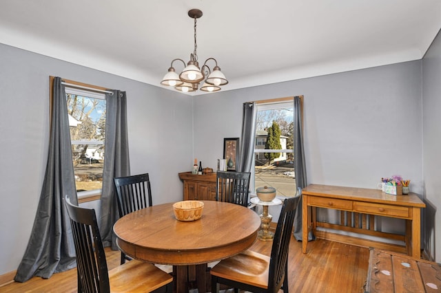 dining space with hardwood / wood-style floors and a notable chandelier